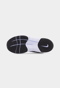 Semelle de chaussure de course noir et blanc avec une surface texturée antidérapante, des rainures flexibles courbées et un petit logo Nike Swoosh sur le talon.