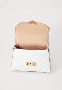 Sac à main en cuir blanc avec motif embossé, quincaillerie dorée et fermoir. Intérieur beige clair avec une poche zippée. Ouvert pour plus de visibilité.