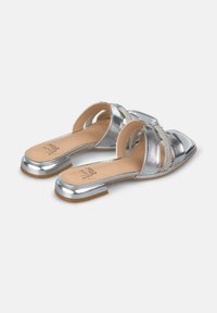 Metalen zilveren sandalen met een open teen ontwerp, voorzien van kruislings straps versierd met rhinestones en een lage blokhak. Platte, gestructureerde zool.
