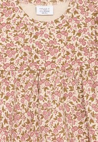 Blomstrete kjole i krem med rosa blomster og grønne blader. Har rund hals, innsnørt midje og myk tekstur.