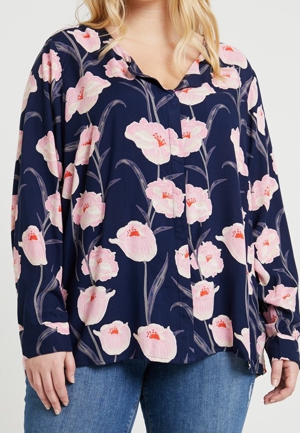 Blusa floreale con sfondo blu navy, caratterizzata da motivi di fiori rosa e bianchi, maniche lunghe e chiusura con bottoni.