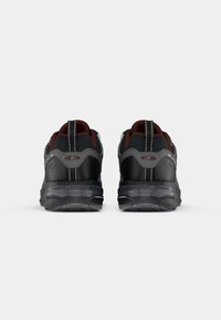 Black and gray athletic shoes with a textured upper, padded collar, reflective accents, and a thick, transparent sole.