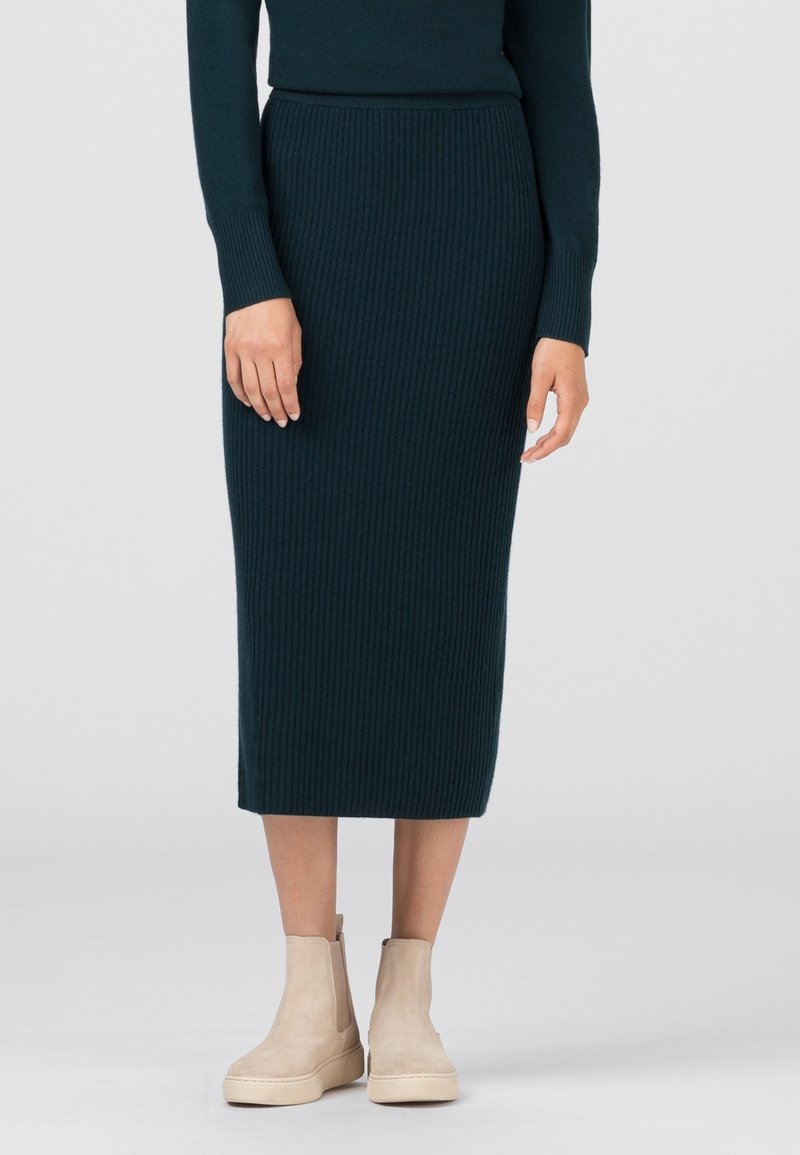 Jupe midi en maille de couleur bleu sarcelle foncé avec une texture côtelée, associée à des bottines beige à finition lisse et doté d'une fermeture éclair latérale.