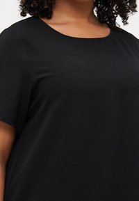 Zwart t-shirt met korte mouwen en een ronde halslijn, gemaakt van een zachte, gestructureerde stof. De pasvorm is ontspannen, wat zorgt voor een gladde silhouet.