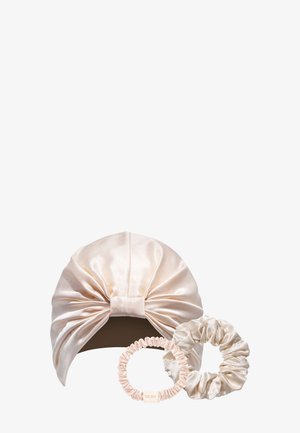 Turban en satin couleur crème avec un grand nœud, accompagné de deux chouchous en satin assortis de tailles différentes.