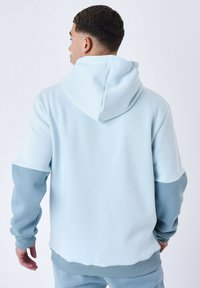 Sudadera azul claro de corte relajado, con capucha y mangas de un azul más oscuro en contraste. Tejido suave con puños y dobladillo acanalados.