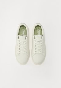 Balti sintetiniai odiniai sportbačiai su lygiu paviršiumi, apvaliu pirštu ir raišteliais. Matomos žalios atminties putų pado vidinės dalys.