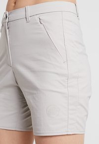 Ljusgrå shorts i ett mjukt tyg, med en ficka med dragkedja, sydda detaljer och en subtil präglad logotyp på benet.