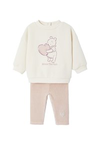 Cremfarbener Pullover mit einem pinken "Winnie the Pooh"-Grafikmotiv, kombiniert mit hellrosa, gerippten Leggings, die ein Herzdesign am Bein aufweisen.