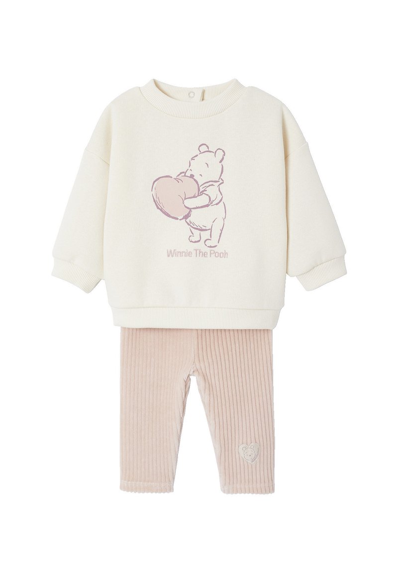 Cremfarbener Pullover mit einem pinken "Winnie the Pooh"-Grafikmotiv, kombiniert mit hellrosa, gerippten Leggings, die ein Herzdesign am Bein aufweisen.