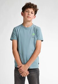 Vaaleansininen puuvillainen t-paita, jossa pieni kirjailtu kuvio, missä on palmupuu ja polkupyörä. Vakio pyöreä pääntie ja lyhyet hihat.