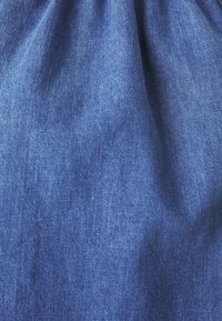 Tessuto denim di un blu profondo, caratterizzato da una consistenza morbida con lievi variazioni, che mostra una superficie liscia e leggermente lucida.