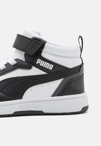 Zwart-witte hoge sneakers van synthetisch leer, met klittenbandsluiting, getextureerde accenten en een rubberen zool. Puma-logo zichtbaar.