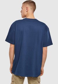 Navy blue cotton T-shirt with short sleeves, round neck, and a relaxed fit; smooth texture with a solid color and no visible patterns.