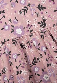 Rosa Stoff mit floralem Muster, das lila, weiße und schwarze Blumen zeigt. Enthält einen gerafften, frilligen Saum und metallische Goldakzente.