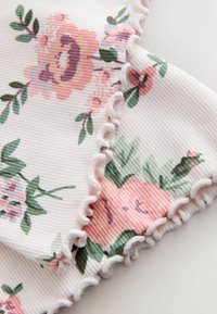 Virágmintás szövet, lágy pasztellszínekben, bordázott textúrával és finom, fehér fodros szegélyekkel. A zöld levelek kiegészítik a virágokat.