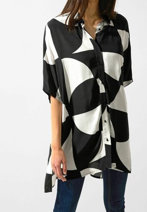 Czarna i biała koszula w geometryczny wzór z krótkimi rękawami, kołnierzykiem i zapięciem na guziki, wykonana z lekkiego materiału o gładkiej teksturze.