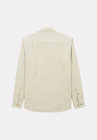Chemise à manches longues en tissu beige clair, dotée d'un poignet boutonné, d'une texture lisse et d'un dos uni avec deux plis aux épaules.