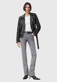 Svart skinnbikerjakke med sølvglidelåser, hvit t-skjorte under, kombinert med grå denim flared jeans og svarte spisse ankelstøvler.