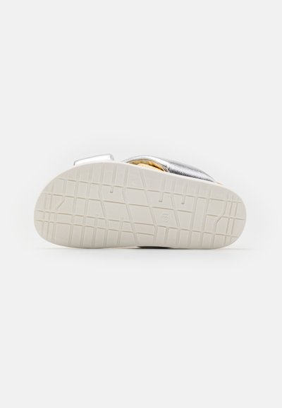 Sandal in argento con suola texturizzata e cinturino regolabile. La suola presenta un motivo a griglia per la trazione.