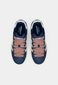 Ναυτικά sneakers με σουέντ ροζ κορδόνια, λευκές ρίγες και μεταλλικές λεπτομέρειες. Διαθέτουν επάνω μέρος από λείο δέρμα και σχεδιασμό με στρογγυλεμένη μύτη.