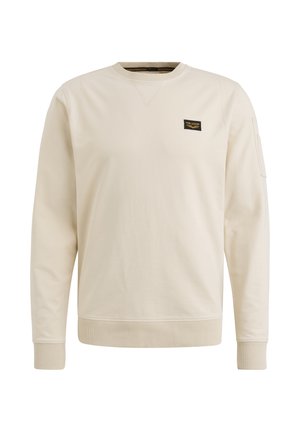 Creme sweatshirt med lange ærmer, ribbede manchetter og kant. Har et lille sort mærke på brystet. Glat bomulds tekstur.