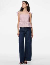 Top peplum a righe con spalline legate, realizzato in tessuto leggero. Abbinato a jeans in denim scuri a gamba larga e sandali neri.