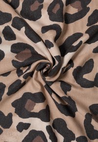 Tkanina s leopardím potiskem na béžovém pozadí, s velkými černými a hnědými skvrnami. Texturovaná, měkká, se záhyby uprostřed.