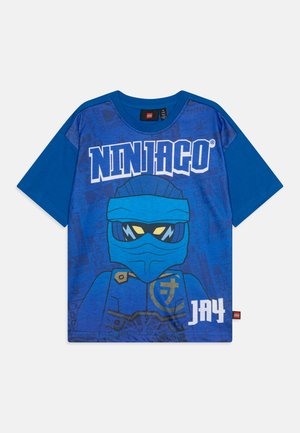 Zila zila kokvilnas T-kreklā ar Ninjago varoni, kurā attēlots ninja z蓝ā maskā un stilizēts teksts "Ninjago Jay" zem tā.
