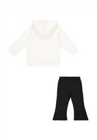 Sudadera blanca con capucha y mangas largas, combinada con leggings negros acampanados. Ambos están hechos de materiales suaves con cinturillas elásticas.