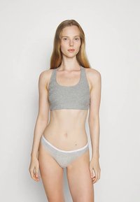 Šedá bavlněná sportovní podprsenka se širokým páskem, v kombinaci se stejnými šedými bikinovými kalhotkami s bílým páskem. Jednoduchý, bezešvý design.
