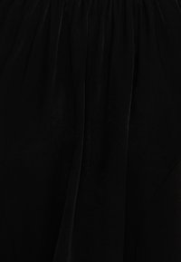 Tissu noir et doux avec une texture lisse, présentant des coutures froncées. Le matériau a un léger éclat qui rehausse son apparence générale.