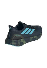 Chaussure de sport noire avec des rayures d'accent bleu, tige en maille, semelle extérieure texturée et motif camouflage en vert et noir. Présente le logo "PUREBOOST".