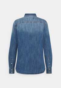 Koszula dżinsowa w średnim odcieniu niebieskiego. Posiada klasyczny kołnierzyk, długie rękawy oraz mankiety zapinane na guziki. Gładka tekstura z subtelnym wyblaknięciem i przeszyciami.