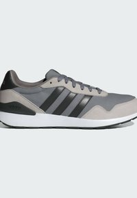 Baskets Adidas grises et noires avec tige en suède et mesh, fermeture à lacets, trois bandes noires sur le côté et semelle blanche amortissante.