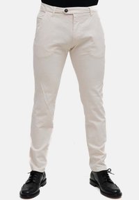 Pantaloni beige chiaro slim fit, realizzati in cotone. Presentano tasche frontali e chiusura con bottone. Indossati con scarpe eleganti nere.