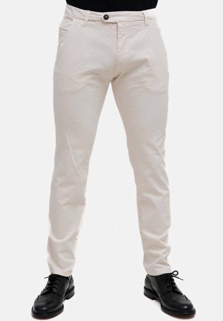 Pantaloni beige chiaro slim fit, realizzati in cotone. Presentano tasche frontali e chiusura con bottone. Indossati con scarpe eleganti nere.