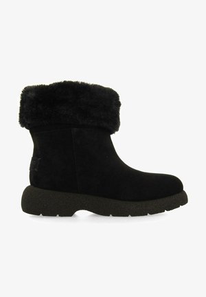 Botines de ante negro con un puño de piel sintética, punta redondeada, suela de goma negra texturizada, con un pequeño parche de logo en el lateral.