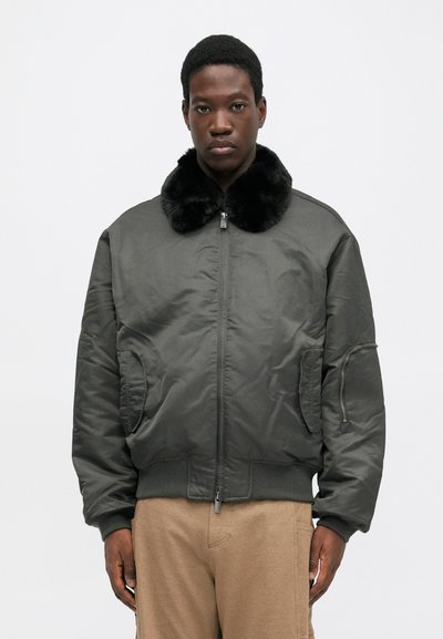 Bomberjacke in Dunkelgrün mit einem Kunstfellkragen, Reißverschluss, seitlichen Taschen, gerippter Bündchen und einer glatten Satin-Oberfläche.