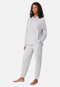 Conjunto de sudadera con capucha y pantalones en gris claro, confeccionado en tejido suave, con bolsillo en la sudadera y puños elásticos en los pantalones. Patrón abstracto sutil.