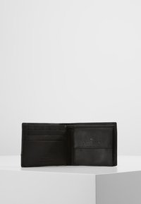 Portefeuille en cuir noir avec plusieurs emplacements pour cartes et une poche pour ID transparente, orné d'un logo en relief et d'une texture lisse.