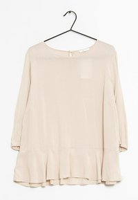 Blusa lunga a maniche con scollo rotondo, colore beige chiaro, orlo peplo e dettaglio a botte sul retro. Realizzata in un tessuto morbido e fluido.