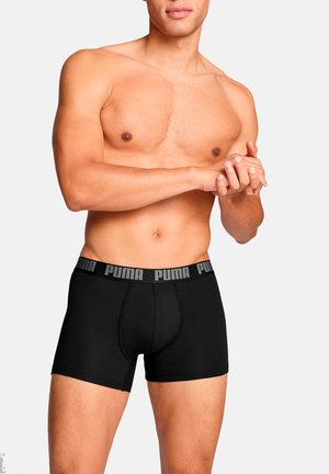 Schwarze Boxershorts aus Stretchstoff mit einem elastischen Bund, der mit einem Logo versehen ist. Das Design beinhaltet einen vorderen Beutel zur Unterstützung.