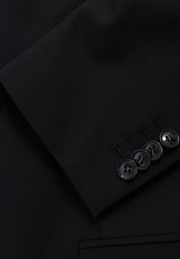 Zwarte colbert mouw met een gladde stof, vier zwarte knopen en gedetailleerde stiksels langs de manchette.