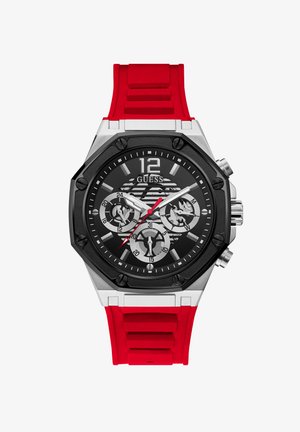 Crni i srebrni analogni sat s crvenim silikonskim remenom. Ima višedijalni prikaz, teksturiranu površinu i istaknute oznake sati.