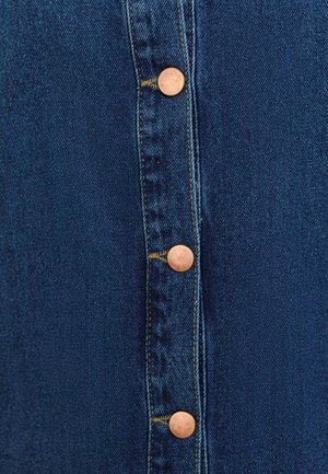 Gonna in denim con cinque bottoni bronzati sul davanti. Tessuto blu scuro con cuciture evidenti e una texture liscia.