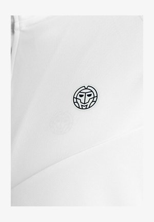 Tela blanca con un pequeño logo redondo en blanco y negro que presenta un rostro estilizado, centrado en la superficie de la tela.