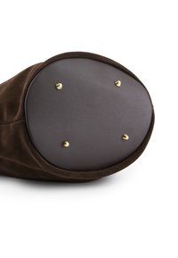 Brązowa torba z zamszu o zaokrąglonym kształcie, z gładką brązową skórzaną podstawą i czterema złotymi metalowymi nóżkami dla wsparcia.