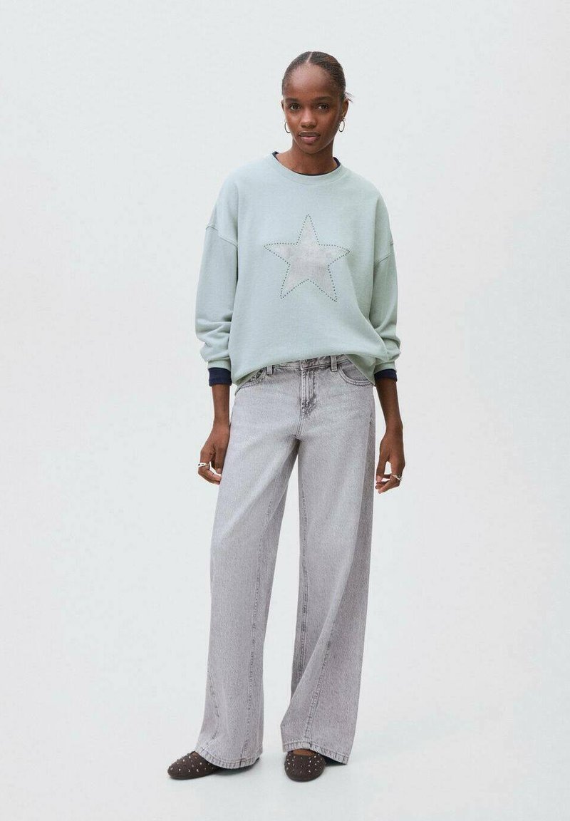 Svetlo modra majica s kapuco z zasnovo z zvezdo, v kombinaciji z visokim pasom sivo širokimi hlačami. Obleka se ponaša z sproščenim krojem in vsakdanjim stilom.