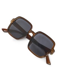 Kvadratna prevelika sončna očala z temno obarvanimi lečami in prozornimi rjavimi plastičnimi okvirji ter kraki.